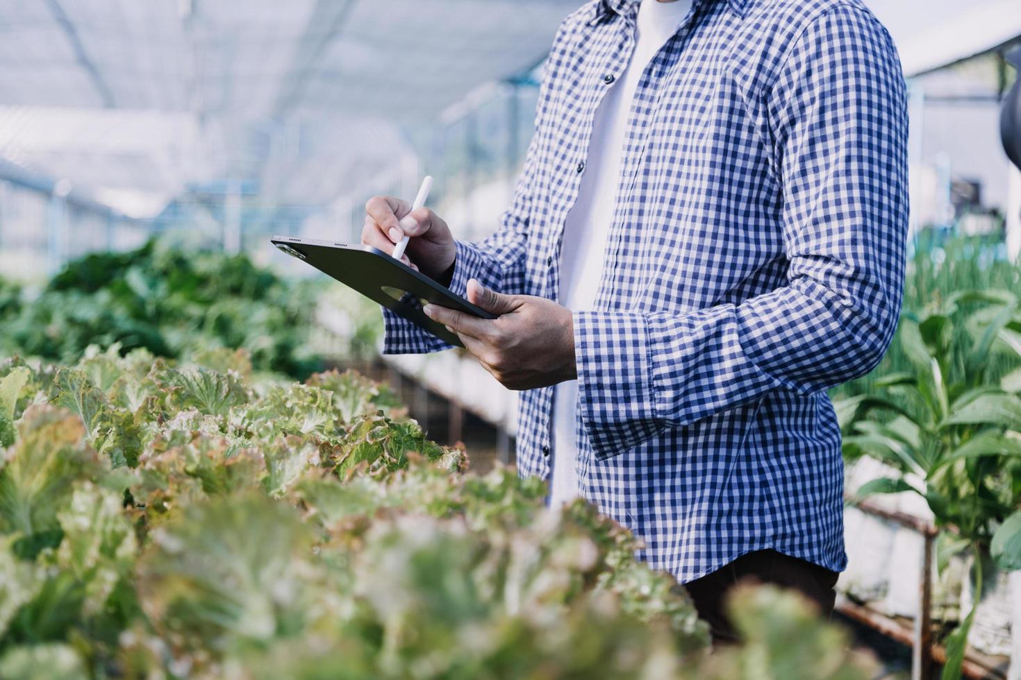 Futuristic businessman farms vegetables and crops using modern AI technology using mobile phones, temperature and humidity sensors, water tracking, climate control, holographic data data icons. photo