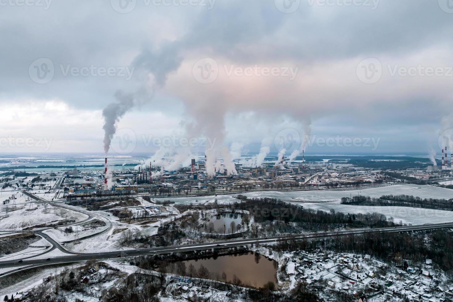 vista aérea panorámica invernal del humo de las tuberías de una planta química o empresa de carpintería. concepto de contaminación del aire y el agua. foto