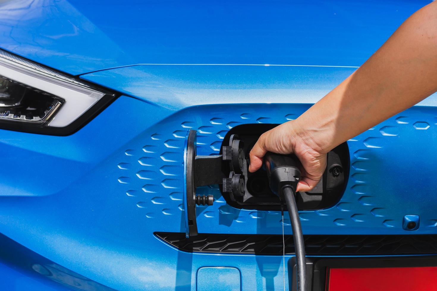 Hand charging car at electric vehicle charging station. photo