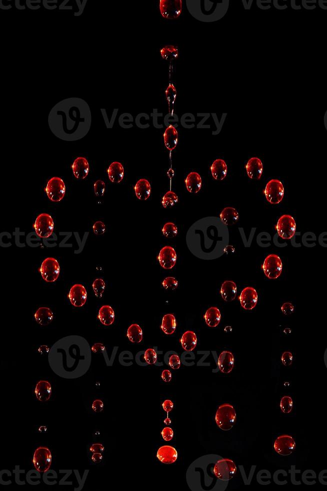 symbol of a crying heart made of red water drops on a dark background, motion blur photo