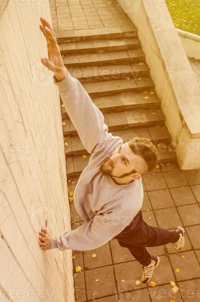 A young guy overcomes obstacles, climbing on concrete walls. The athlete practices parkour, training in street conditions. The concept of sports subcultures among youth photo