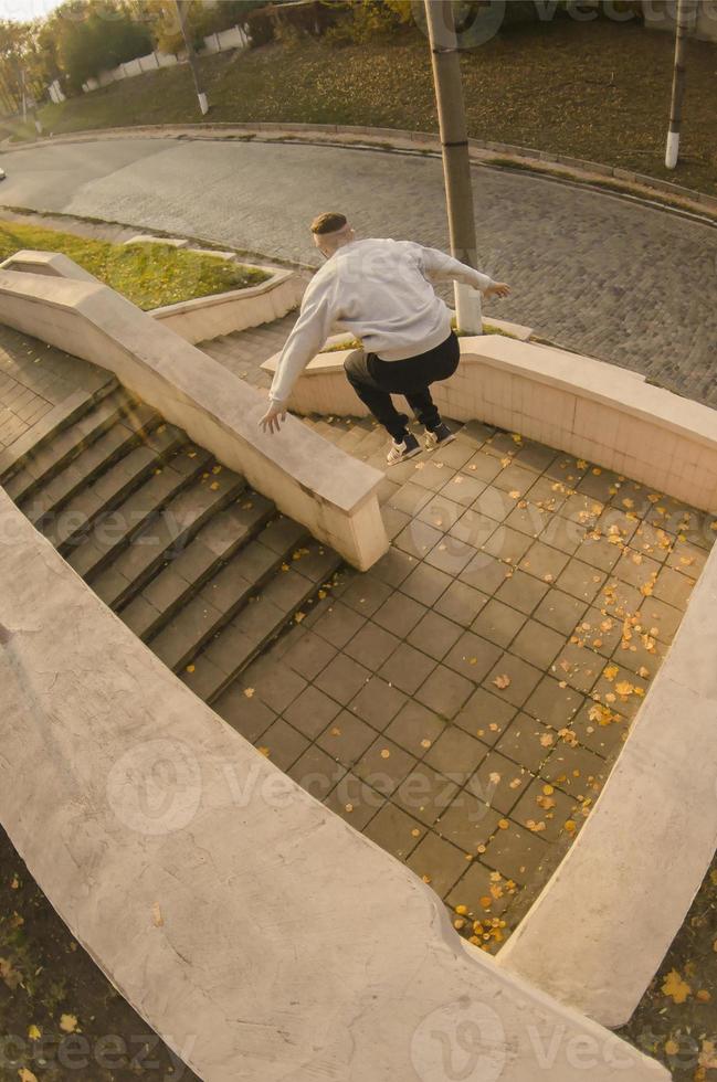 A young guy performs a jump through the space between the concrete parapets. The athlete practices parkour, training in street conditions. The concept of sports subcultures among youth photo