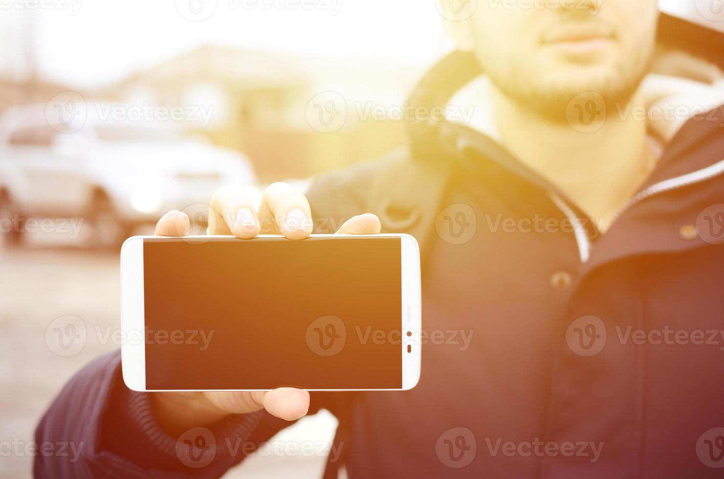 A young guy demonstrates a smartphone display on the background photo