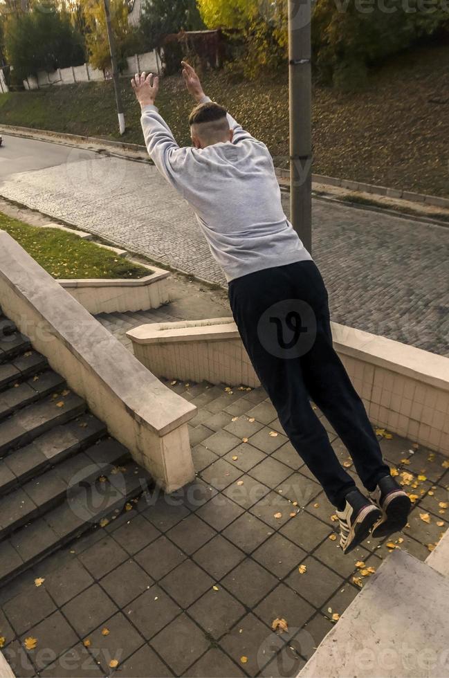 A young guy performs a jump through the space between the concrete parapets. The athlete practices parkour, training in street conditions. The concept of sports subcultures among youth photo