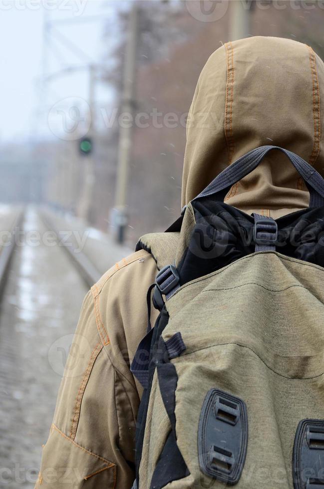 A man with a large backpack goes ahead on the railway track duri photo