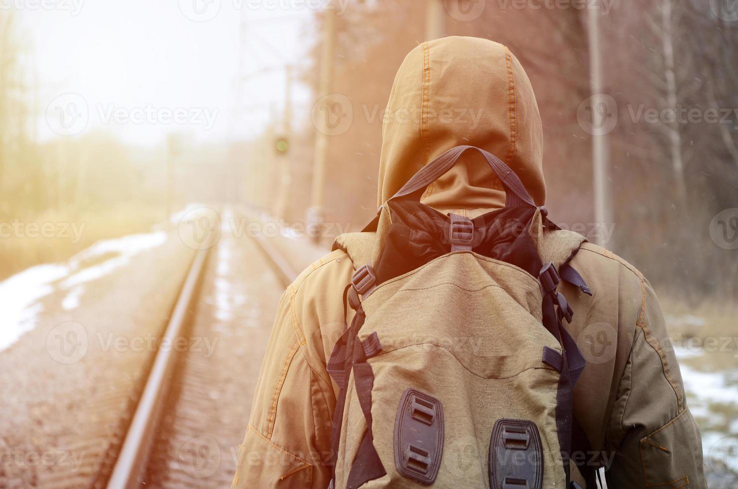 A man with a large backpack goes ahead on the railway track duri photo