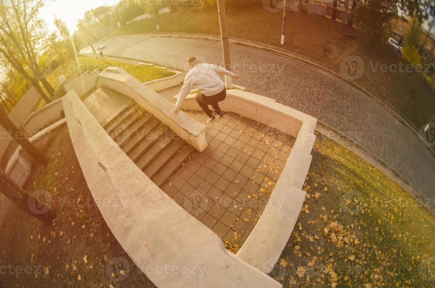 A young guy performs a jump through the space between the concrete parapets. The athlete practices parkour, training in street conditions. The concept of sports subcultures among youth photo