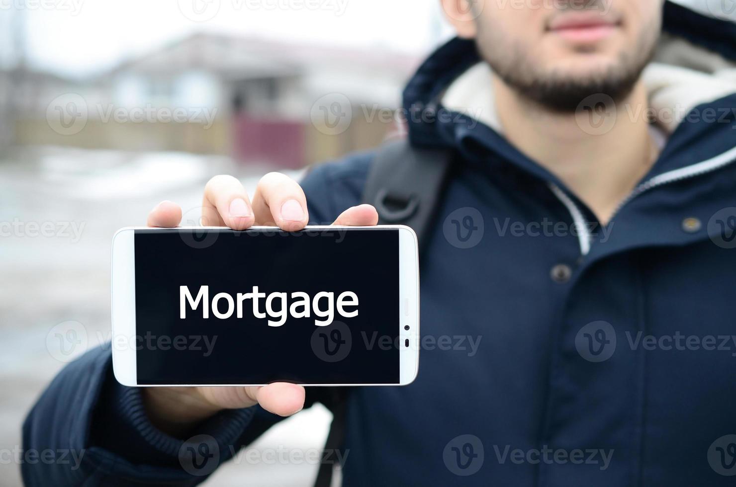 A young guy shows an inscription on the smartphone's display on photo