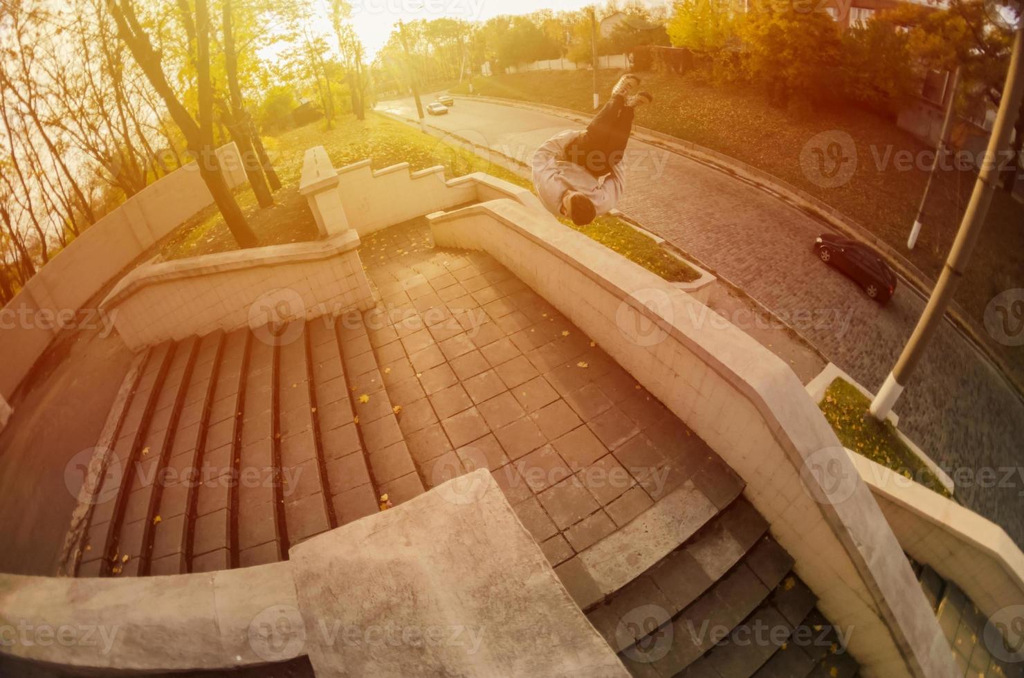 A young guy performs a side flip in the autumn park. The athlete practices parkour, training in street conditions. The concept of sports subcultures among youth photo