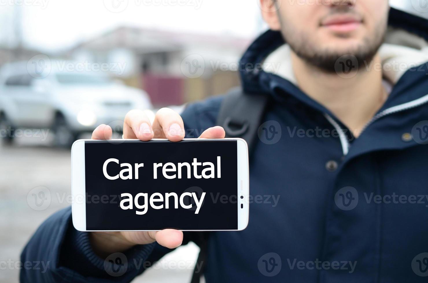 A young guy shows an inscription on the smartphone's display on photo