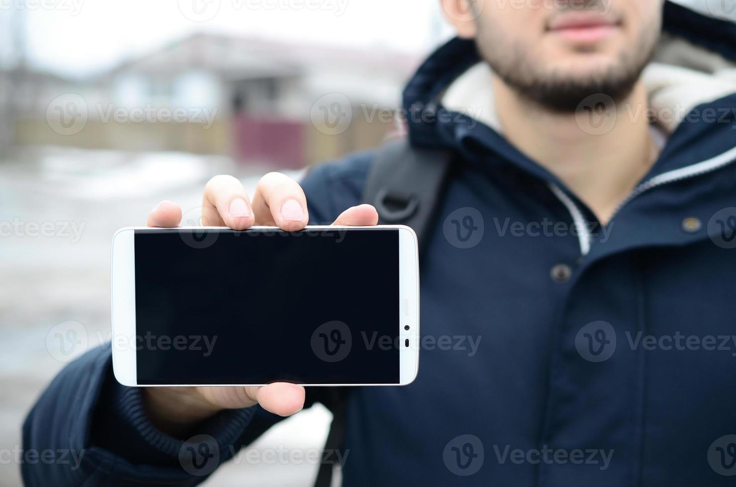 A young guy demonstrates a smartphone display on the background photo