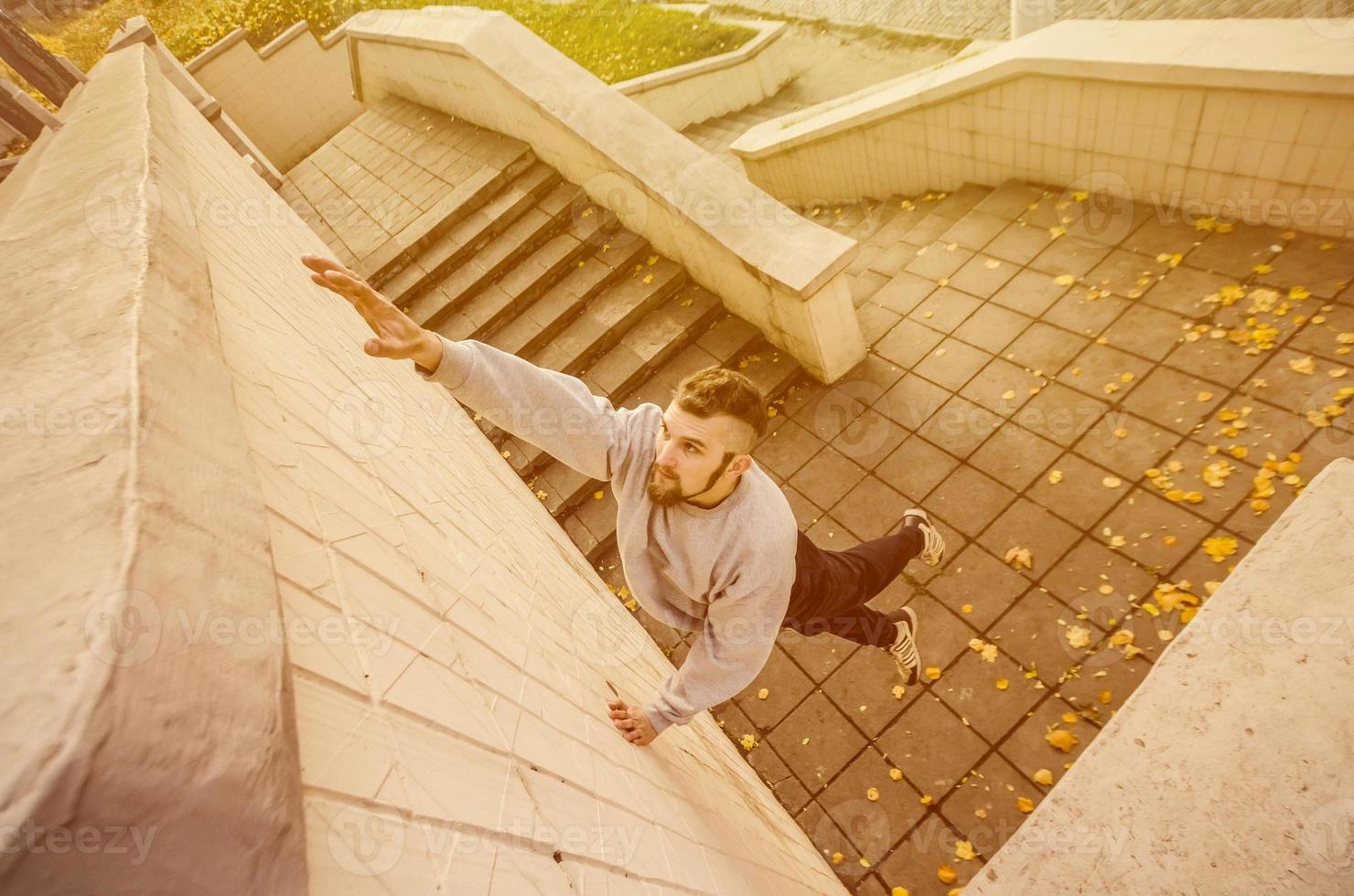 un joven supera obstáculos, trepando por paredes de hormigón. el atleta practica parkour, entrenando en condiciones de calle. el concepto de subculturas deportivas entre los jóvenes foto