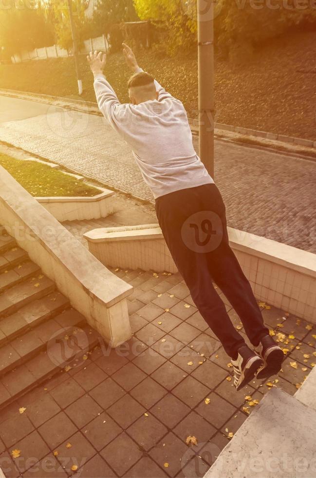 A young guy performs a jump through the space between the concrete parapets. The athlete practices parkour, training in street conditions. The concept of sports subcultures among youth photo