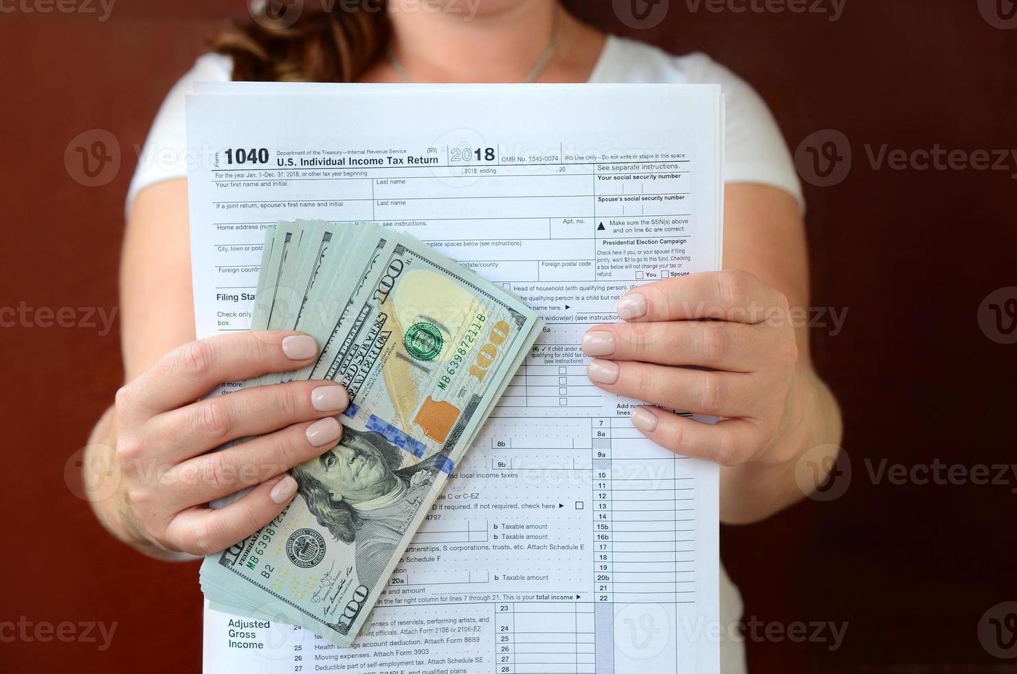 The girl holds in her hands the tax form and a large number of dollar bills photo