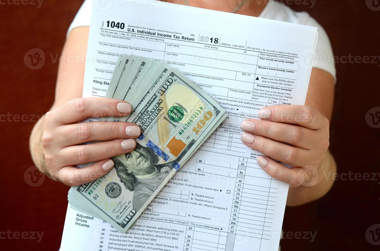 The girl holds in her hands the tax form and a large number of dollar bills photo