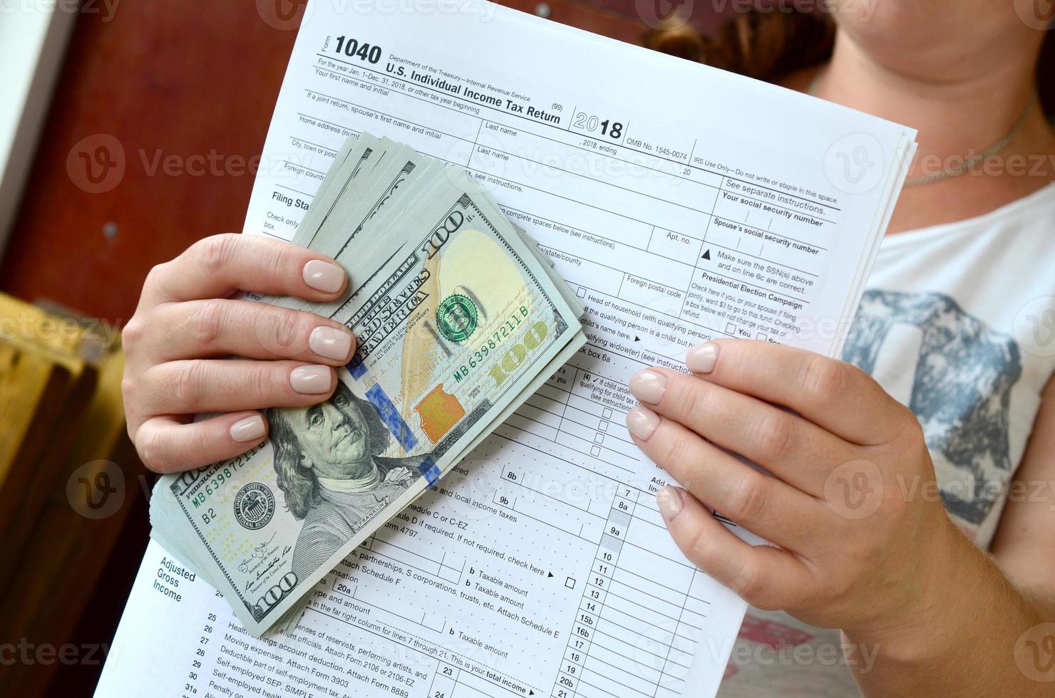 The girl holds in her hands the tax form and a large number of dollar bills photo