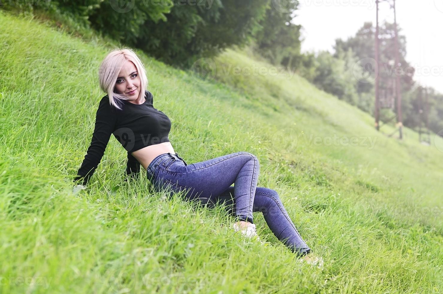 Portrait of a young blond woman with short hair sitting on a gre photo