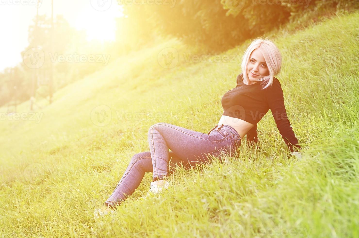 Portrait of a young blond woman with short hair sitting on a gre photo