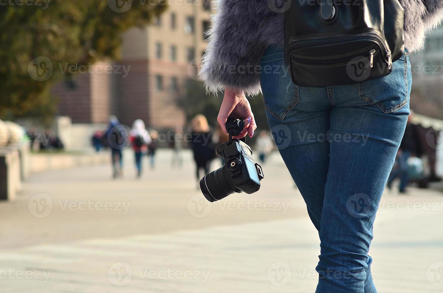 Rear view of a girl with a digital camera on a crowded street ba photo