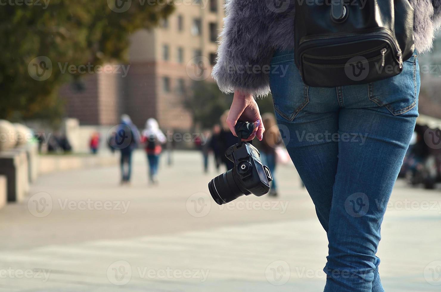 Rear view of a girl with a digital camera on a crowded street ba photo