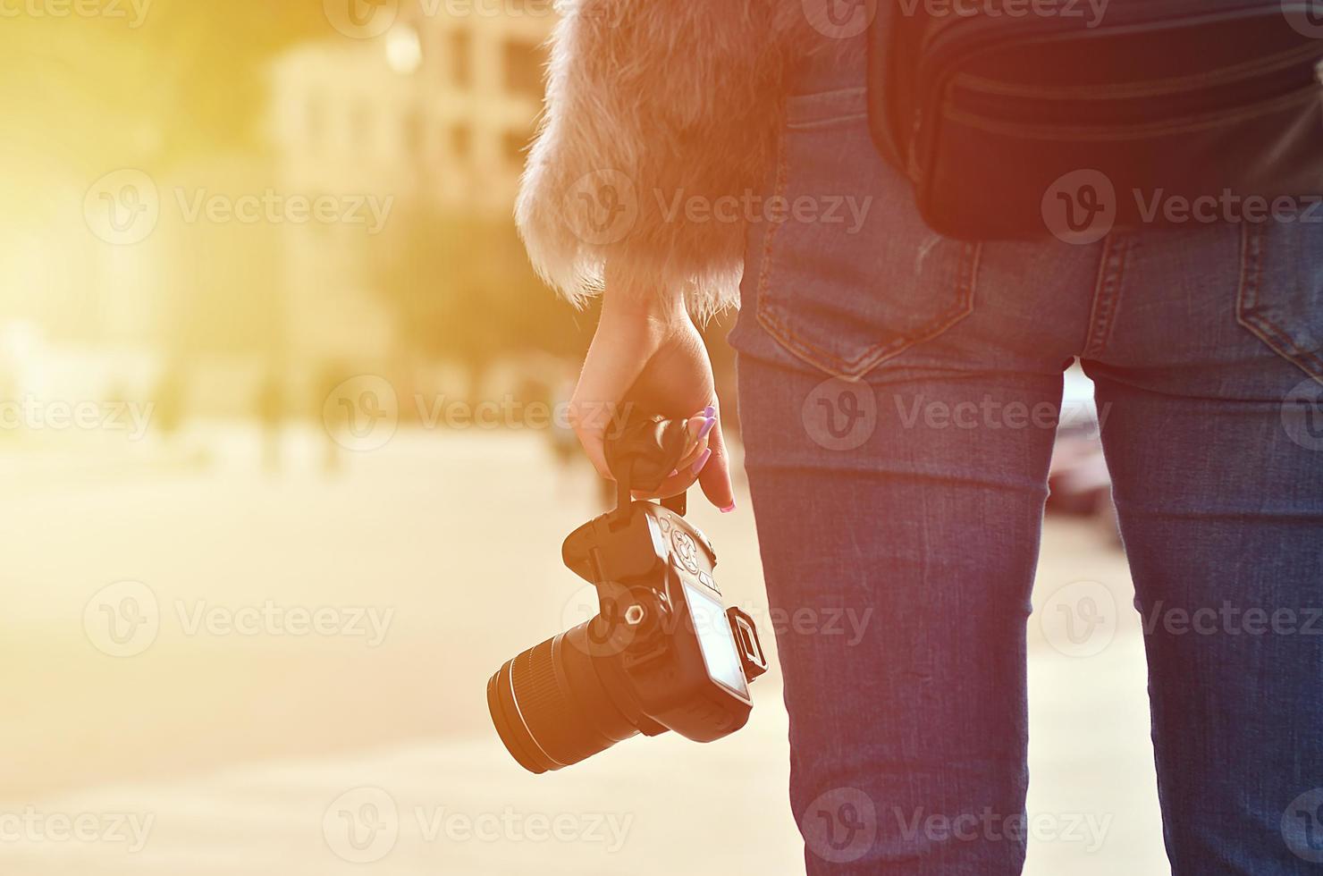 Rear view of a girl with a digital camera on a crowded street ba photo