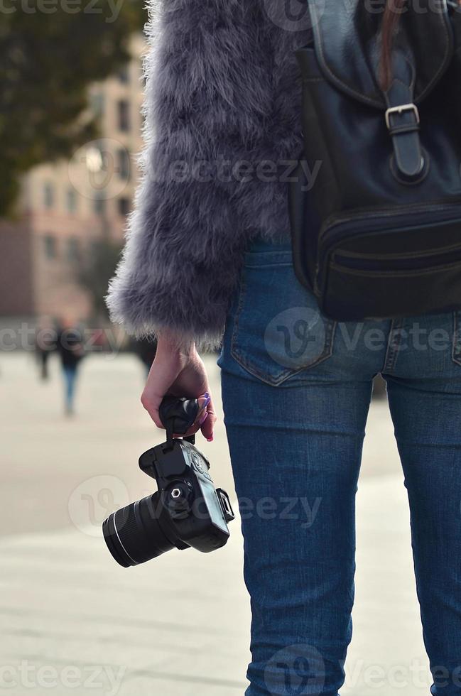 Rear view of a girl with a digital camera on a crowded street ba photo