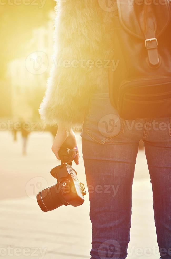 Rear view of a girl with a digital camera on a crowded street ba photo
