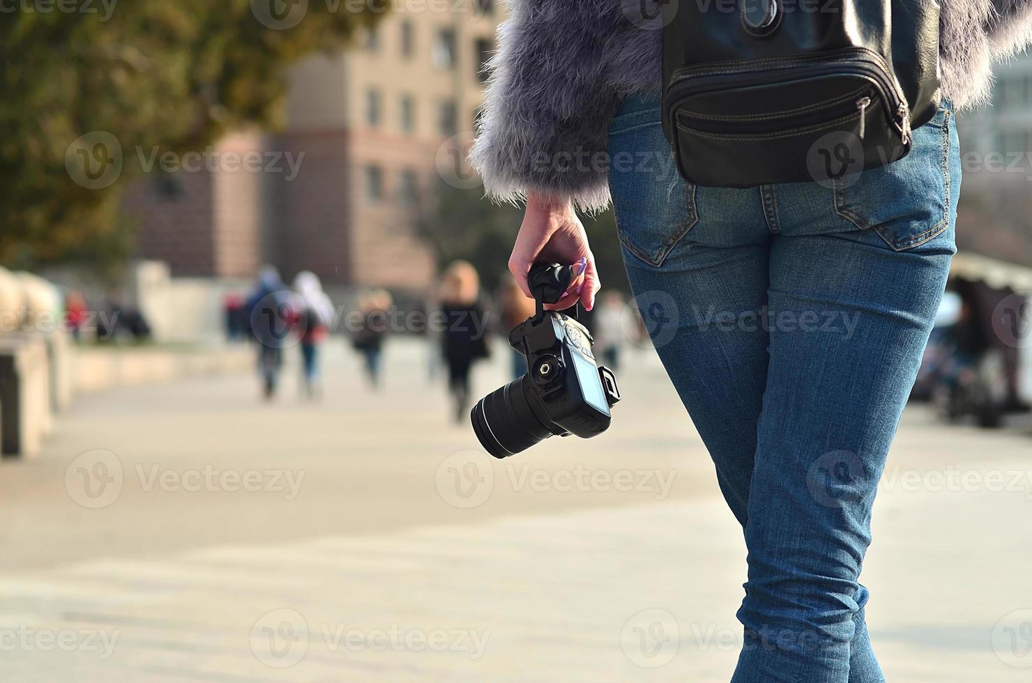 Rear view of a girl with a digital camera on a crowded street ba photo