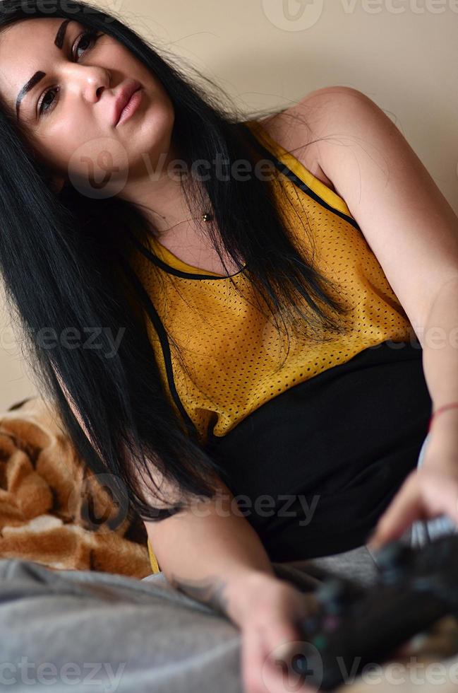 A young girl plays video games with a black joystick with many b photo