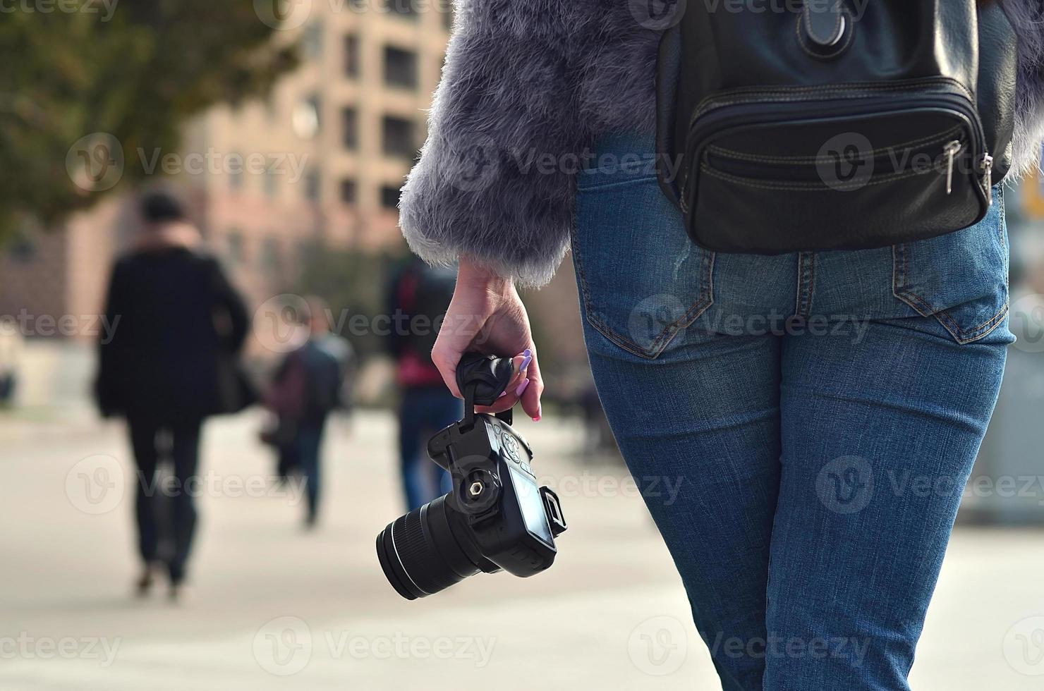 Rear view of a girl with a digital camera on a crowded street ba photo