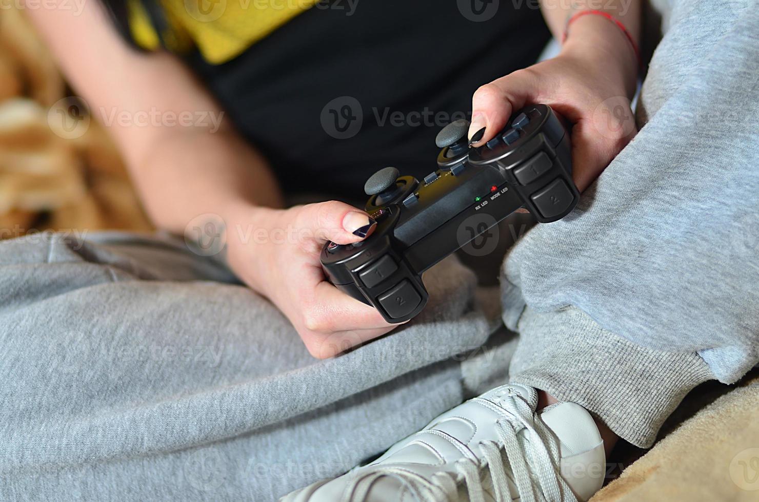 controlador de juego negro moderno en manos de una joven sentada foto