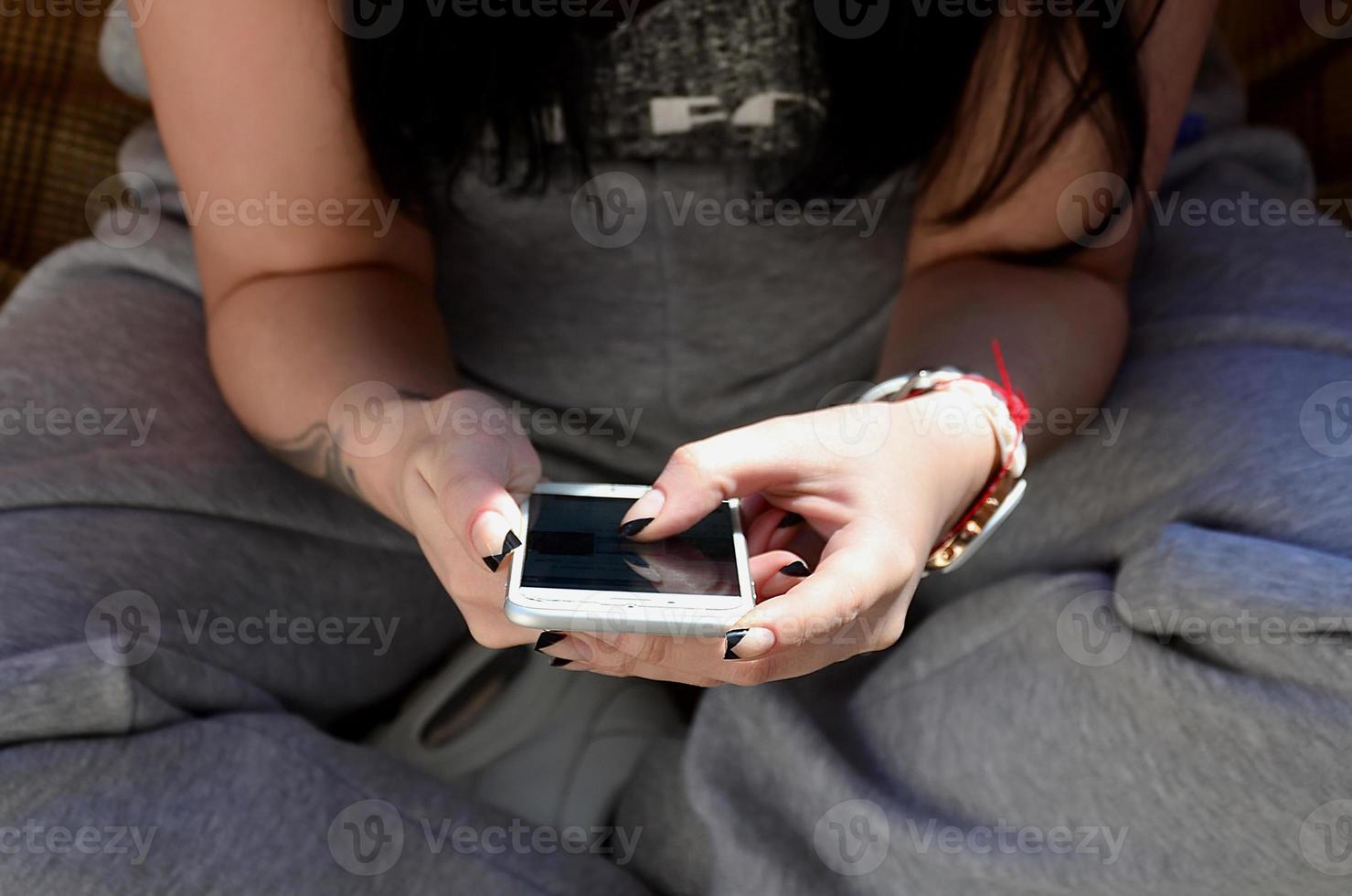 The brunette girl uses a modern touch smartphone photo