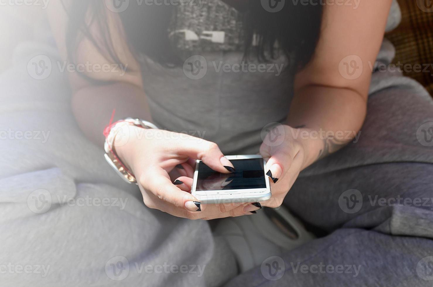 The brunette girl uses a modern touch smartphone photo