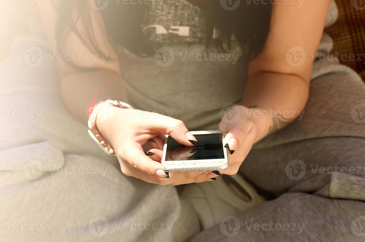 The brunette girl uses a modern touch smartphone photo