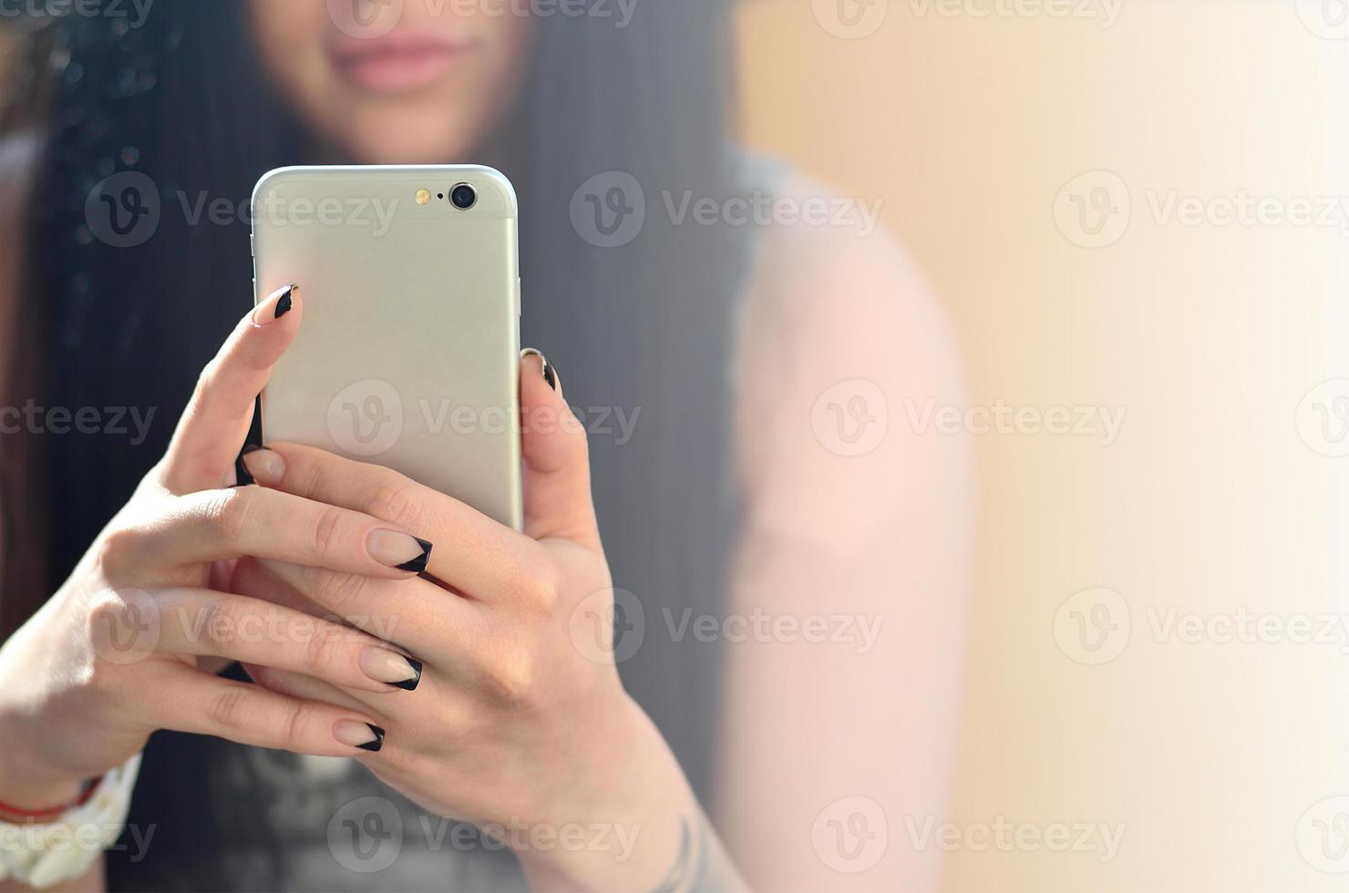 la chica morena usa un teléfono inteligente táctil moderno foto