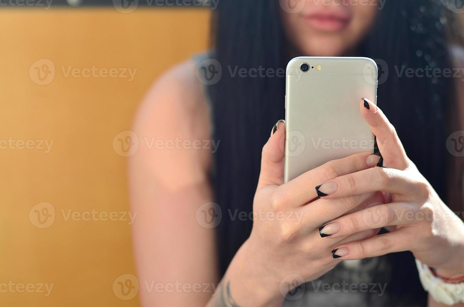 The brunette girl uses a modern touch smartphone photo