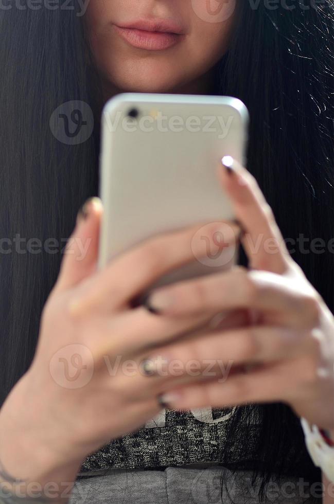 la chica morena usa un teléfono inteligente táctil moderno foto