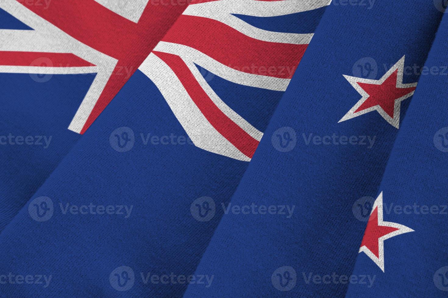 New Zealand flag with big folds waving close up under the studio light indoors. The official symbols and colors in banner photo