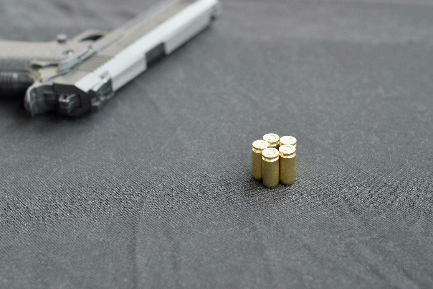 9mm bullets and pistol lie on a black fabric. A set shooting range items or a self-defense kit photo