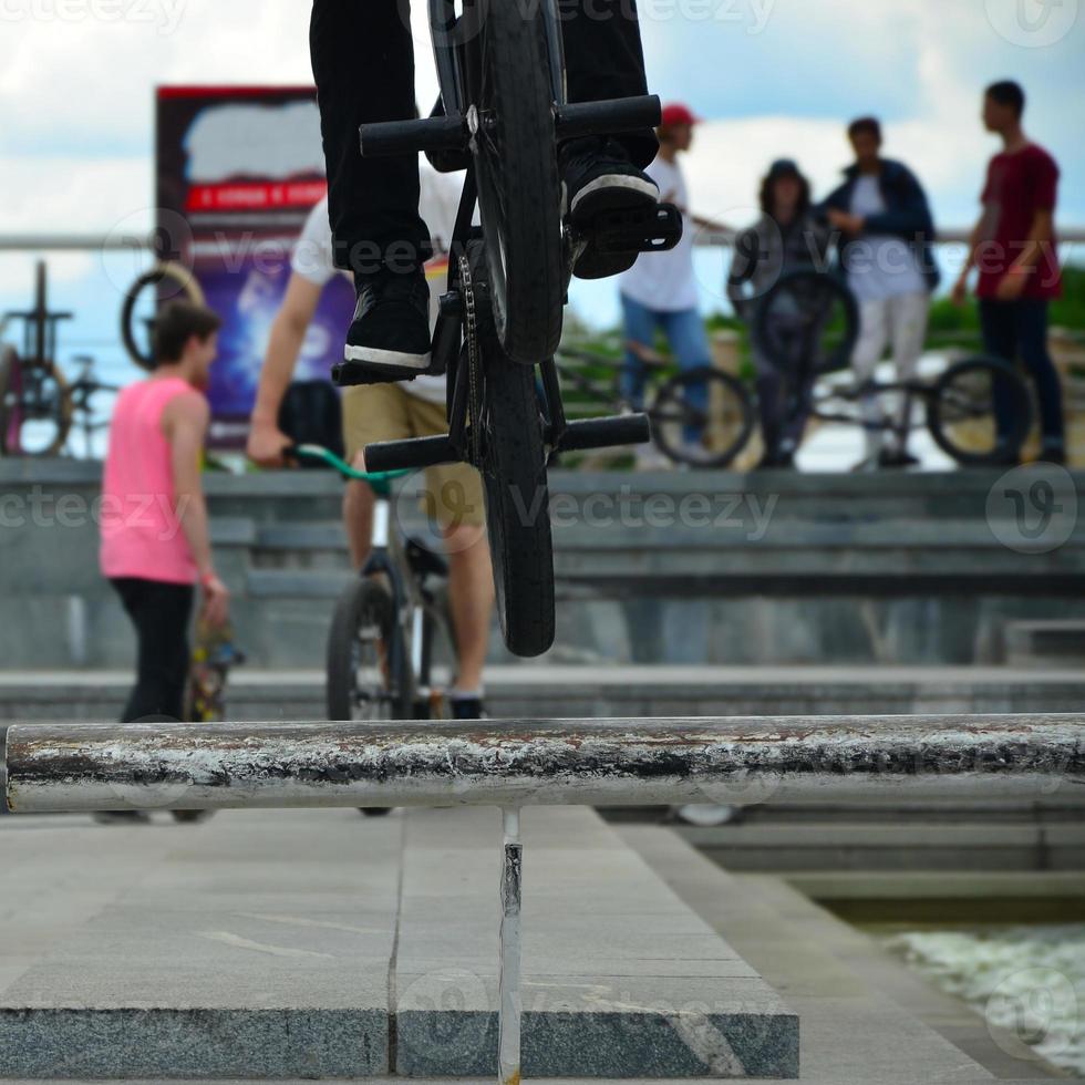 A cyclist jumps over a pipe on a BMX bike. A lot of people with bicycles in the background. Extreme sports concept photo