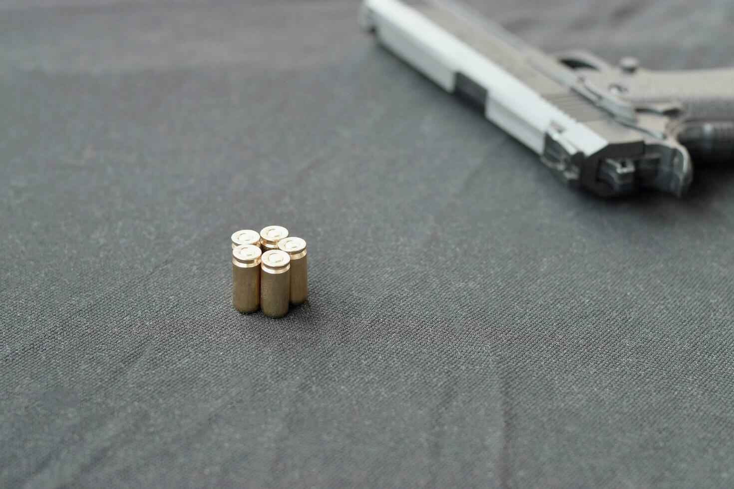 9mm bullets and pistol lie on a black fabric. A set shooting range items or a self-defense kit photo