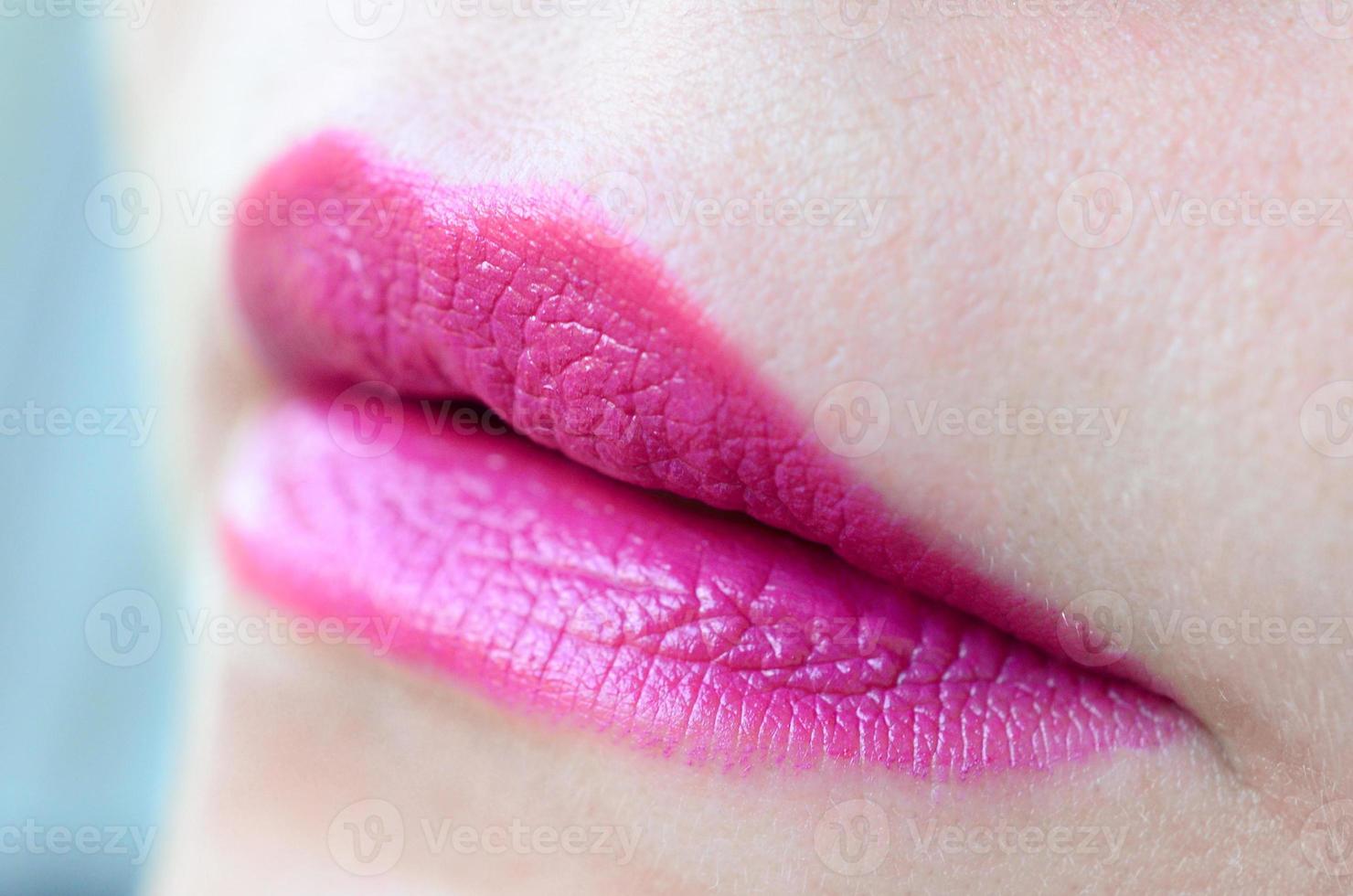 Close up shot of woman lips with glossy fuchsia lipstick photo