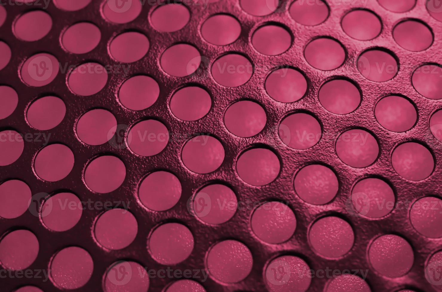 Black metal computer case panel mesh with holes on background. Abstract close up image Image toned in Viva Magenta, color of the 2023 year photo