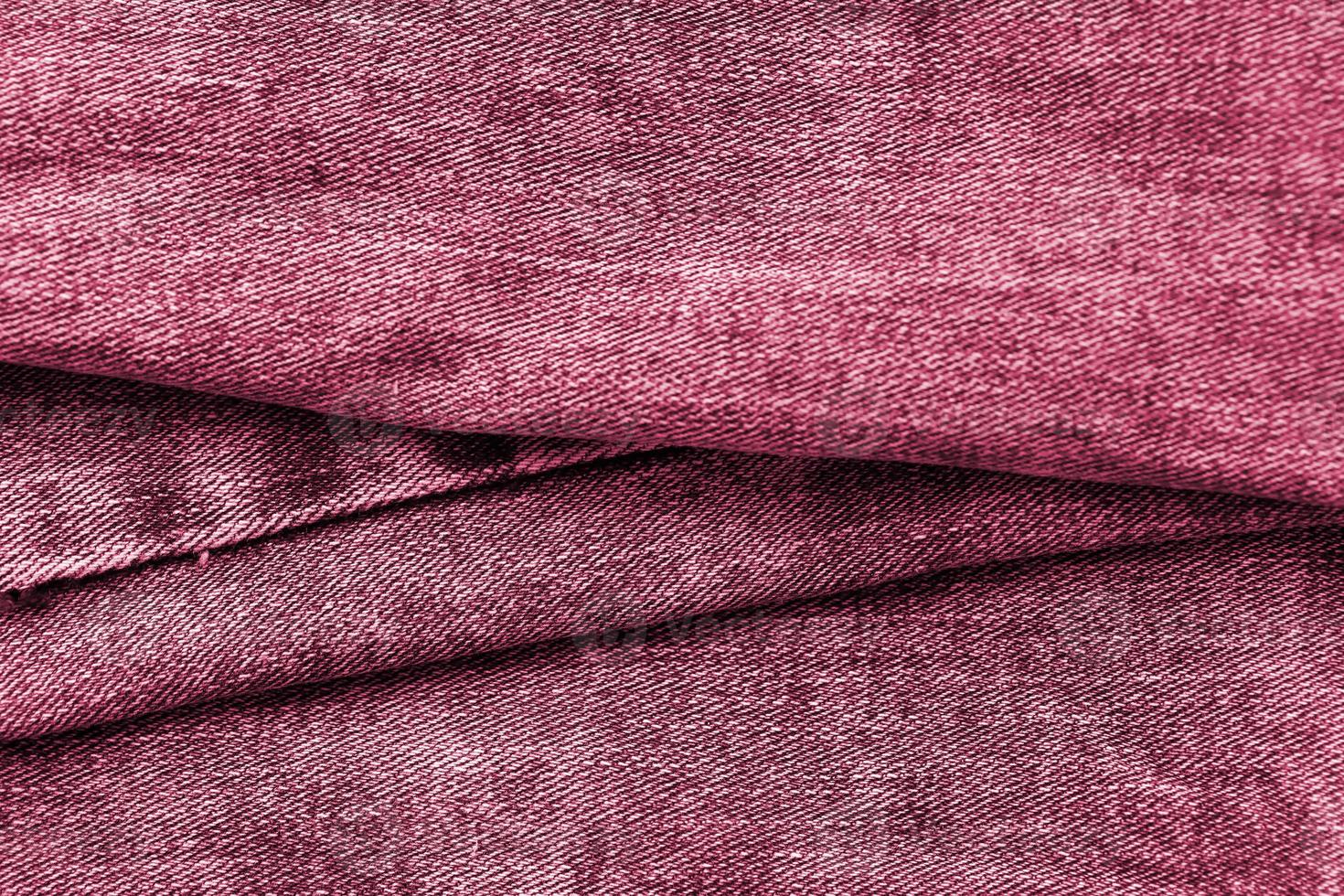 Detailed abstract texture of dark blue denim cloth. Background image of old used denim trousers fabric Image toned in Viva Magenta, color of the 2023 year photo