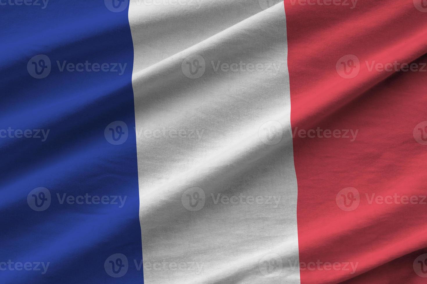 France flag with big folds waving close up under the studio light indoors. The official symbols and colors in banner photo