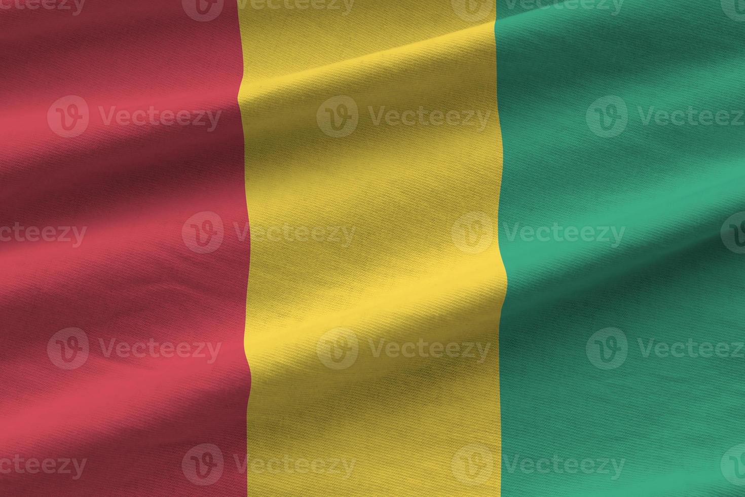 Guinea flag with big folds waving close up under the studio light indoors. The official symbols and colors in banner photo