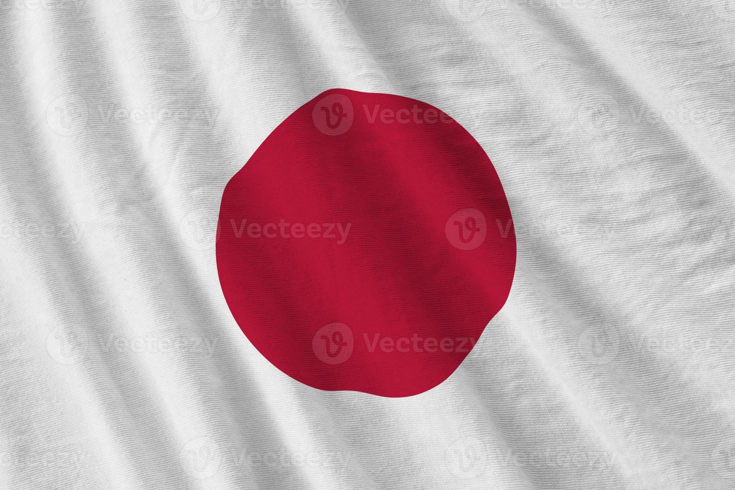 Japan flag with big folds waving close up under the studio light indoors. The official symbols and colors in banner photo