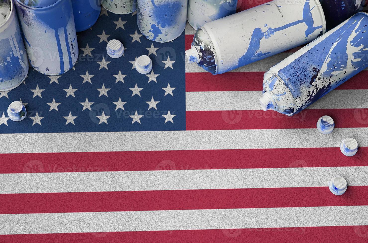 bandera de los estados unidos de américa y pocas latas de aerosol usadas para pintar graffiti. concepto de cultura de arte callejero foto