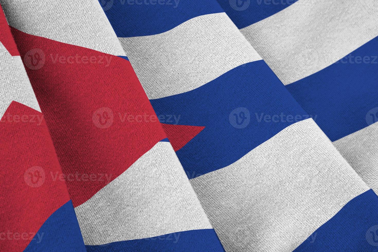 Cuba flag with big folds waving close up under the studio light indoors. The official symbols and colors in banner photo