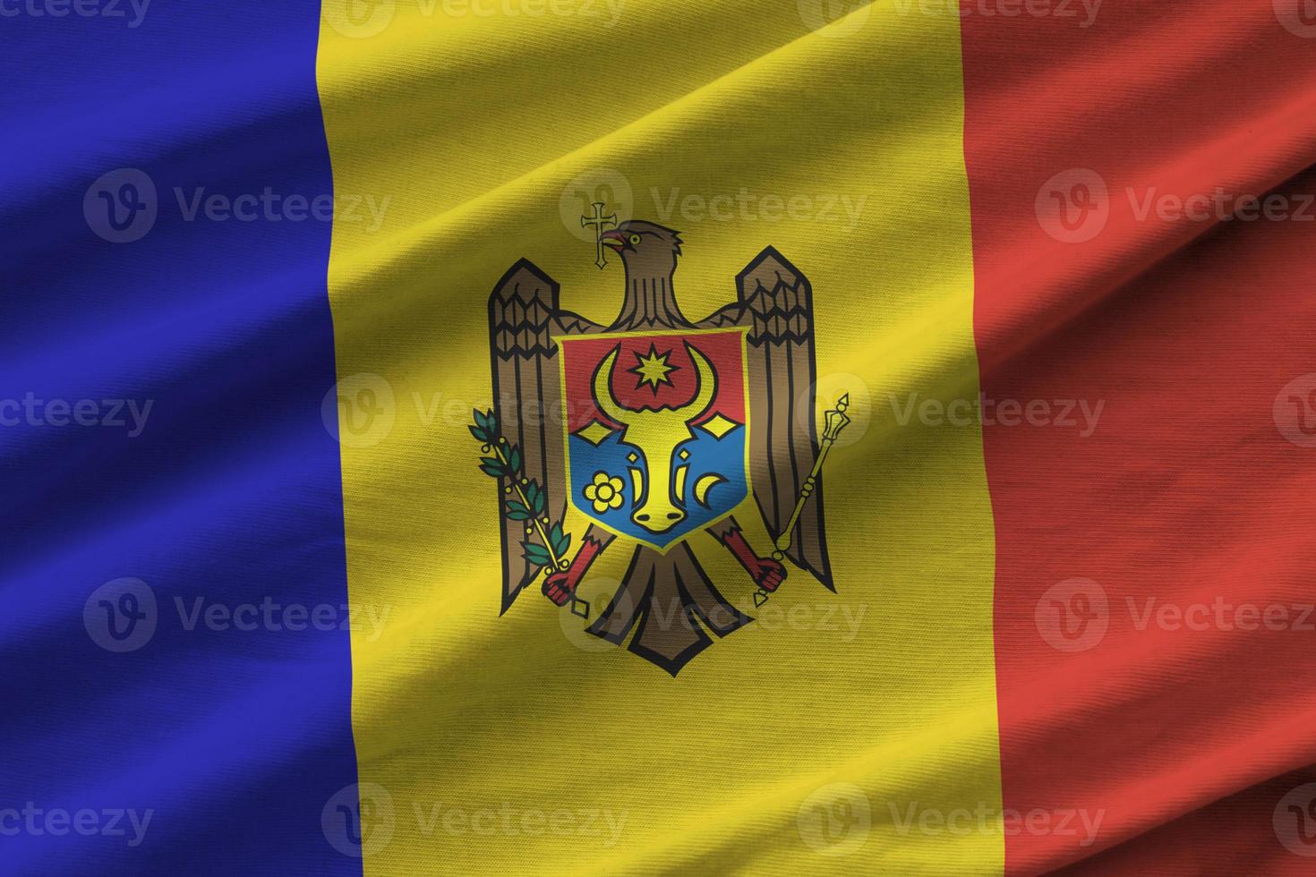 Moldova flag with big folds waving close up under the studio light indoors. The official symbols and colors in banner photo